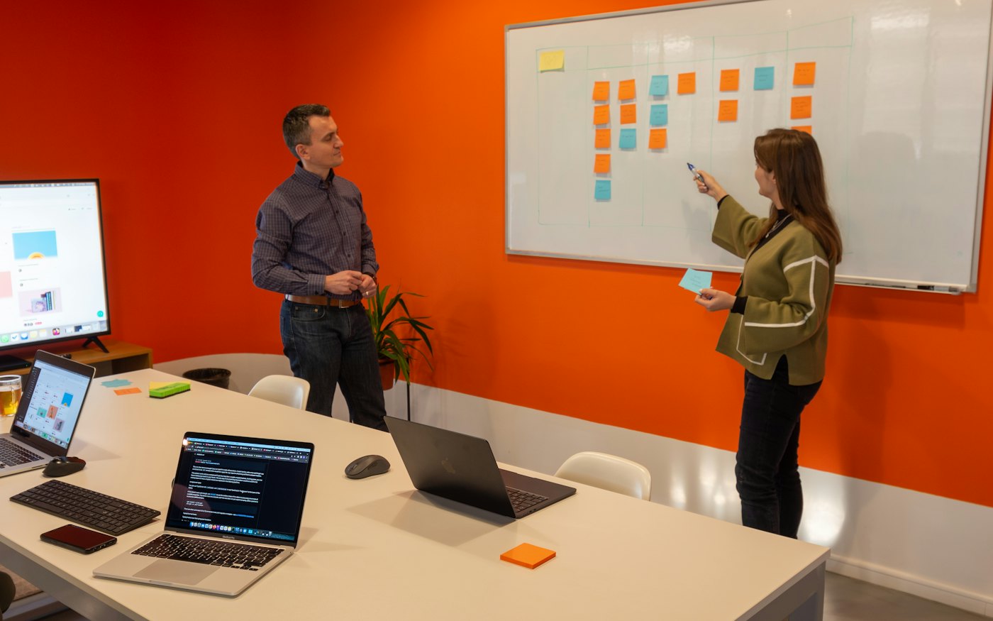 Two colleagues planning work on a sticky-note board