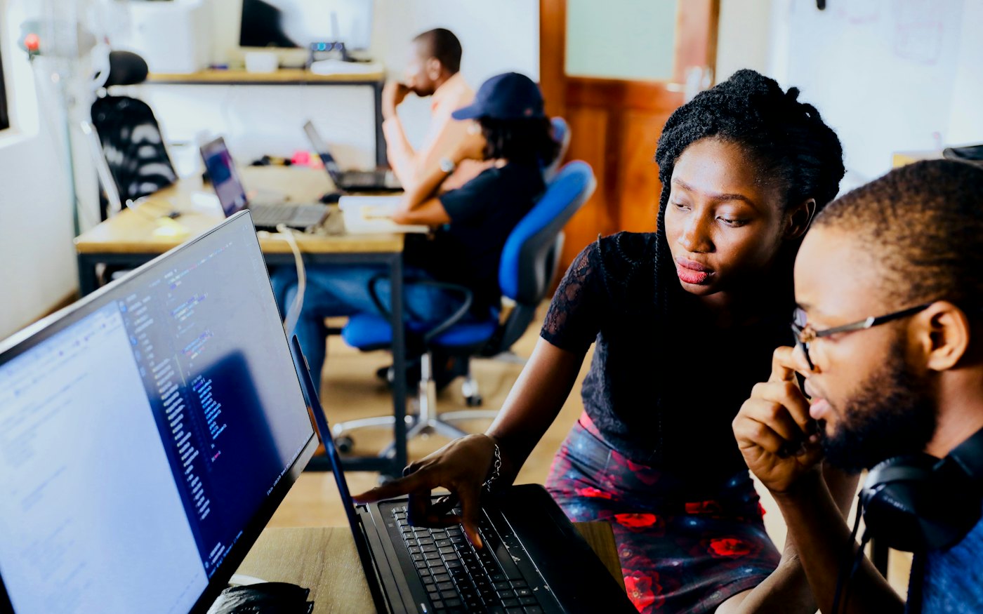 Two colleagues working through code at a monitor